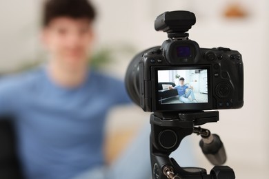 Photo of Teenage blogger explaining something while streaming at home, focus on camera