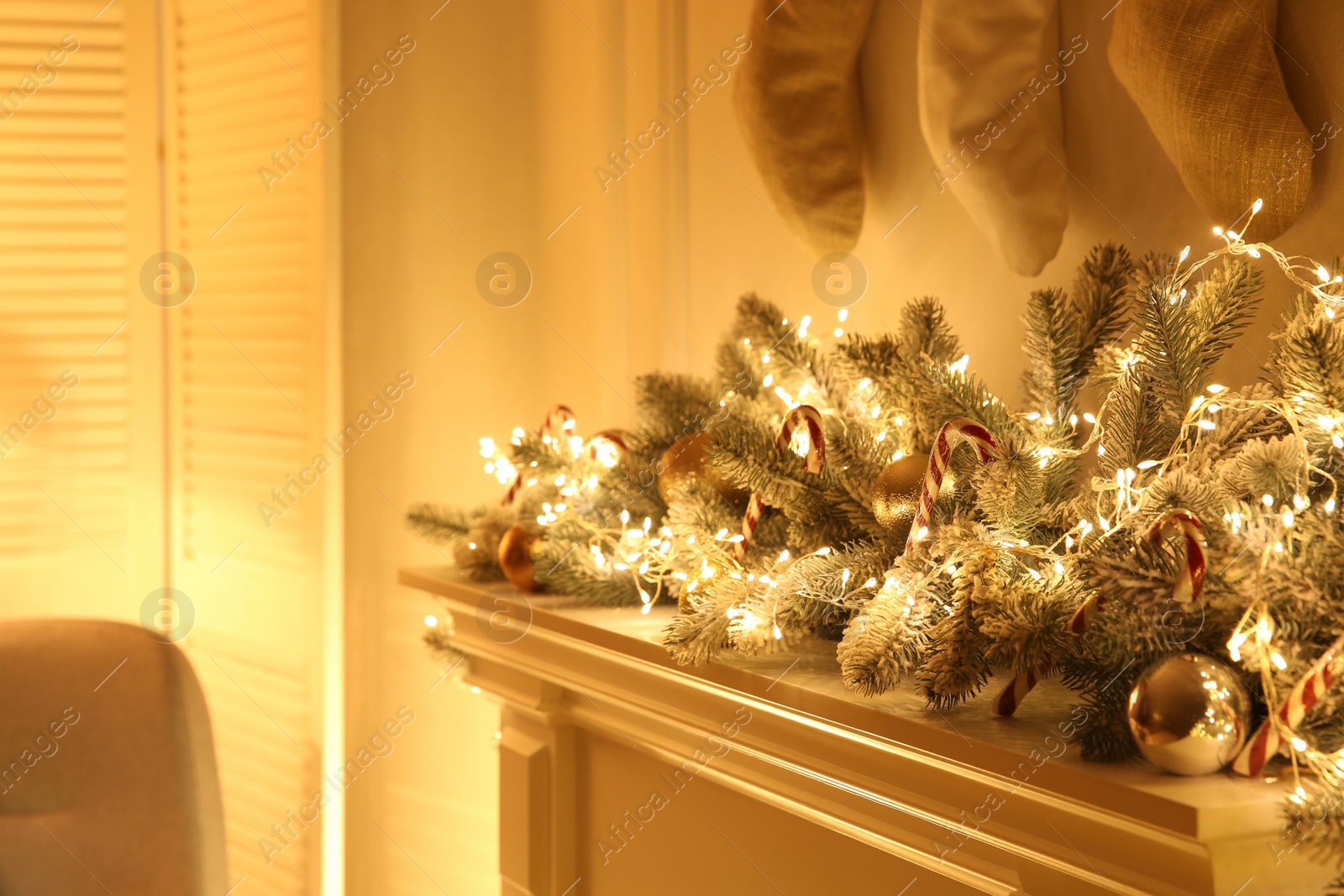 Photo of Beautiful decoration of fir tree branches, candy canes, fairy lights and Christmas balls in room, closeup