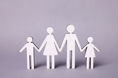 Photo of Figures of family stainding on lilac background. Insurance concept