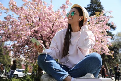 Photo of Young woman listening to audiobook in park