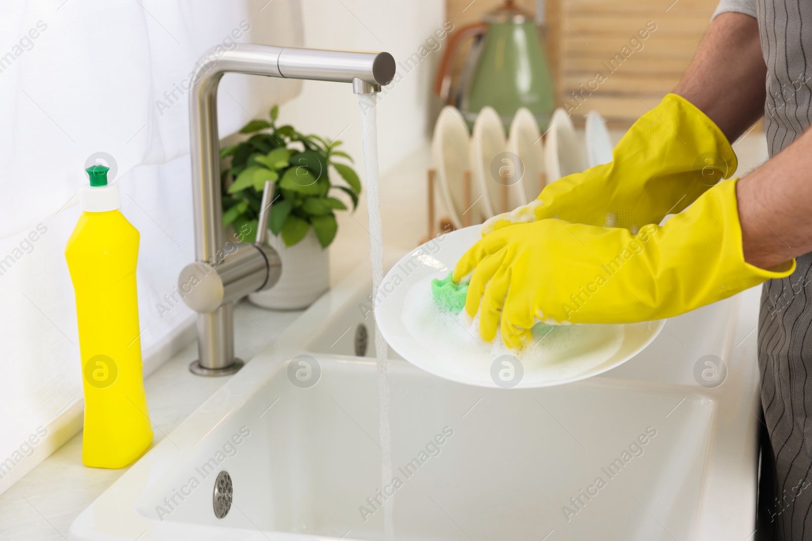 Photo of Man washing plate above sink in kitchen, closeup