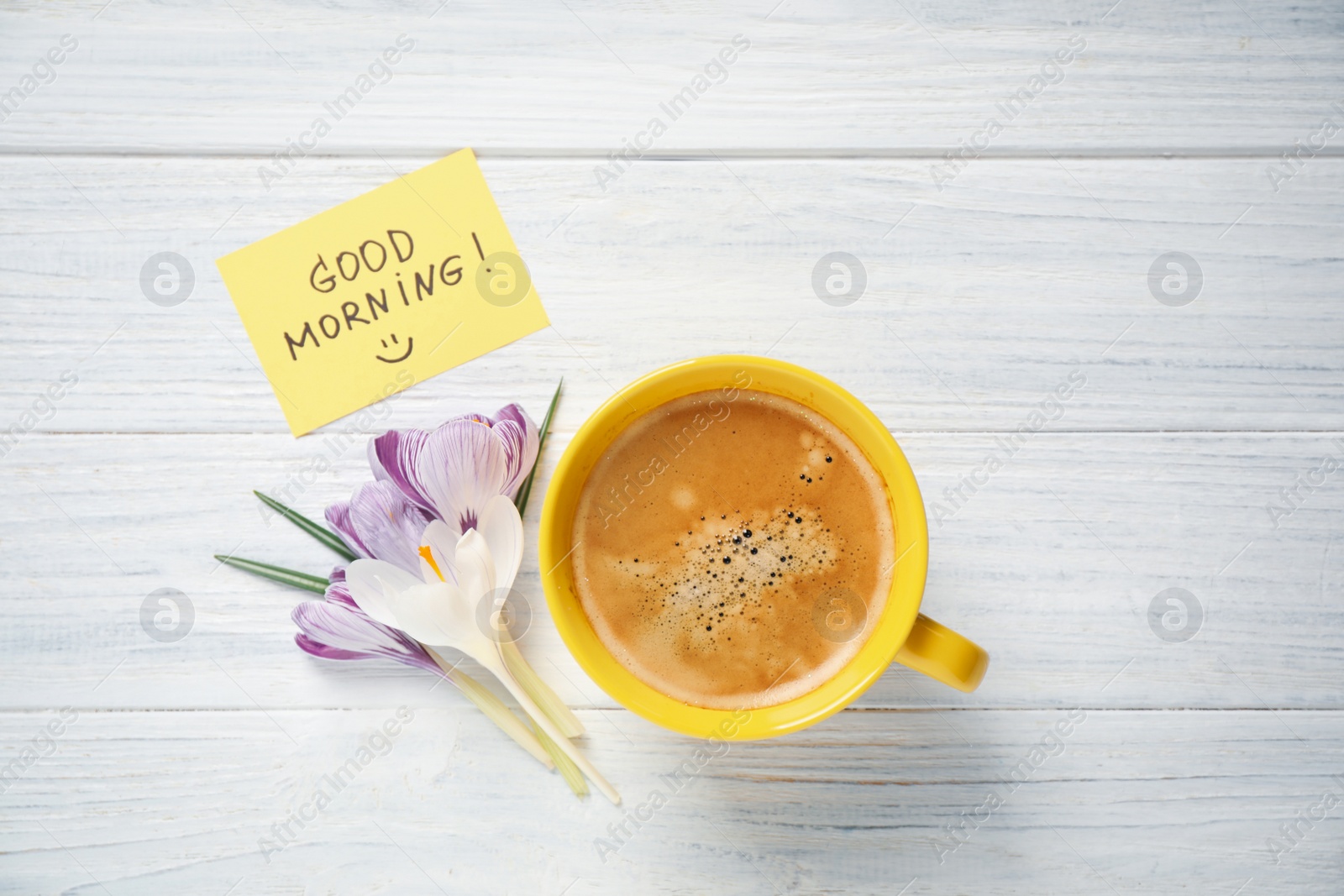 Photo of Delicious coffee, flowers and card with GOOD MORNING wish on white wooden table, flat lay