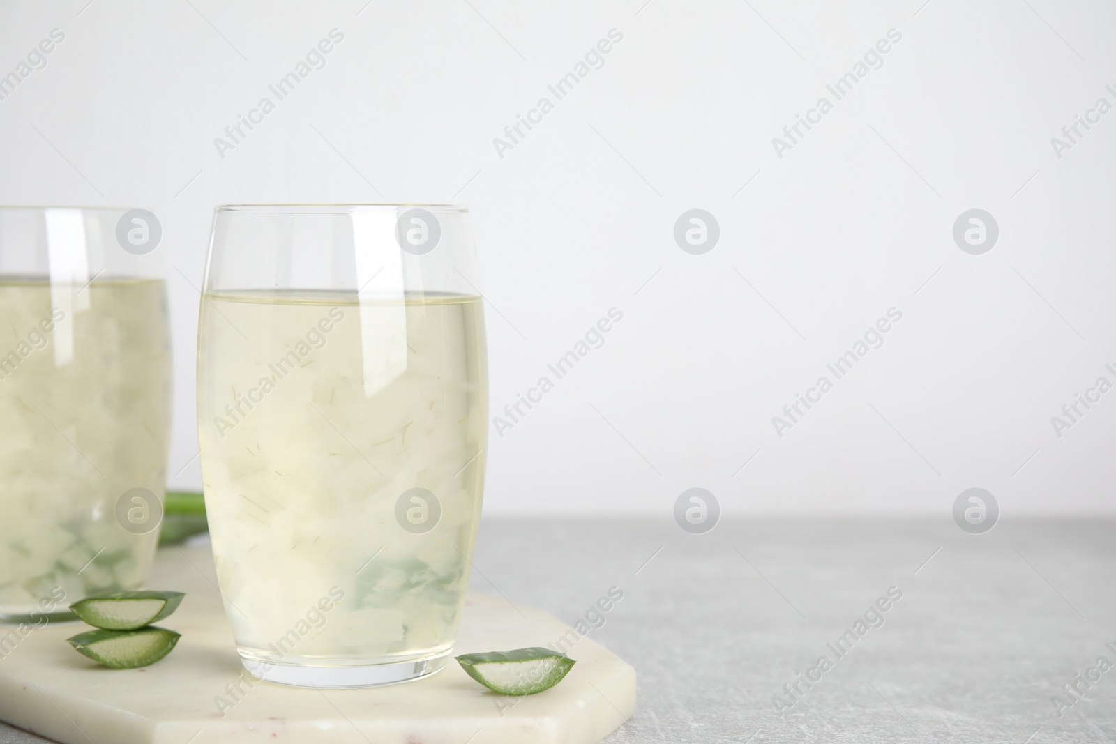 Photo of Fresh aloe drink in glasses on light grey table. Space for text