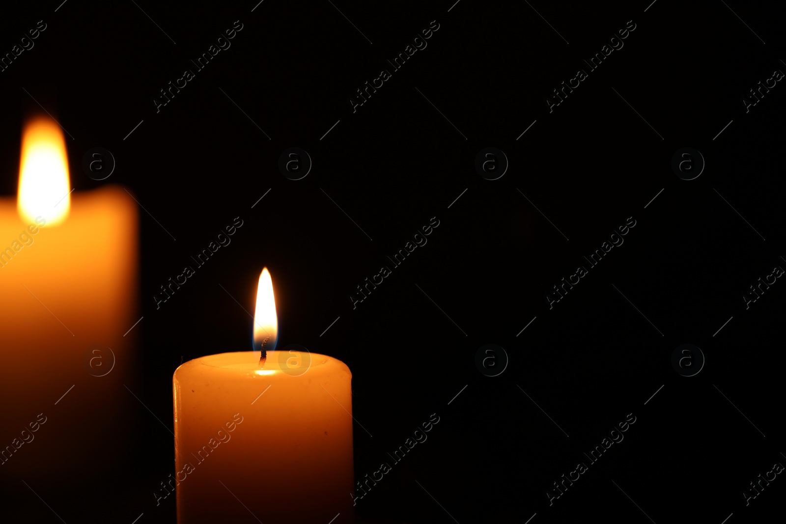 Photo of Burning candle on black background, closeup. Space for text