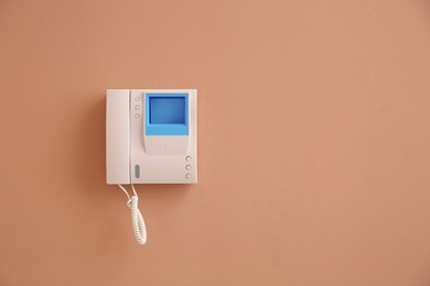 Modern intercom system with handset on beige wall, space for text