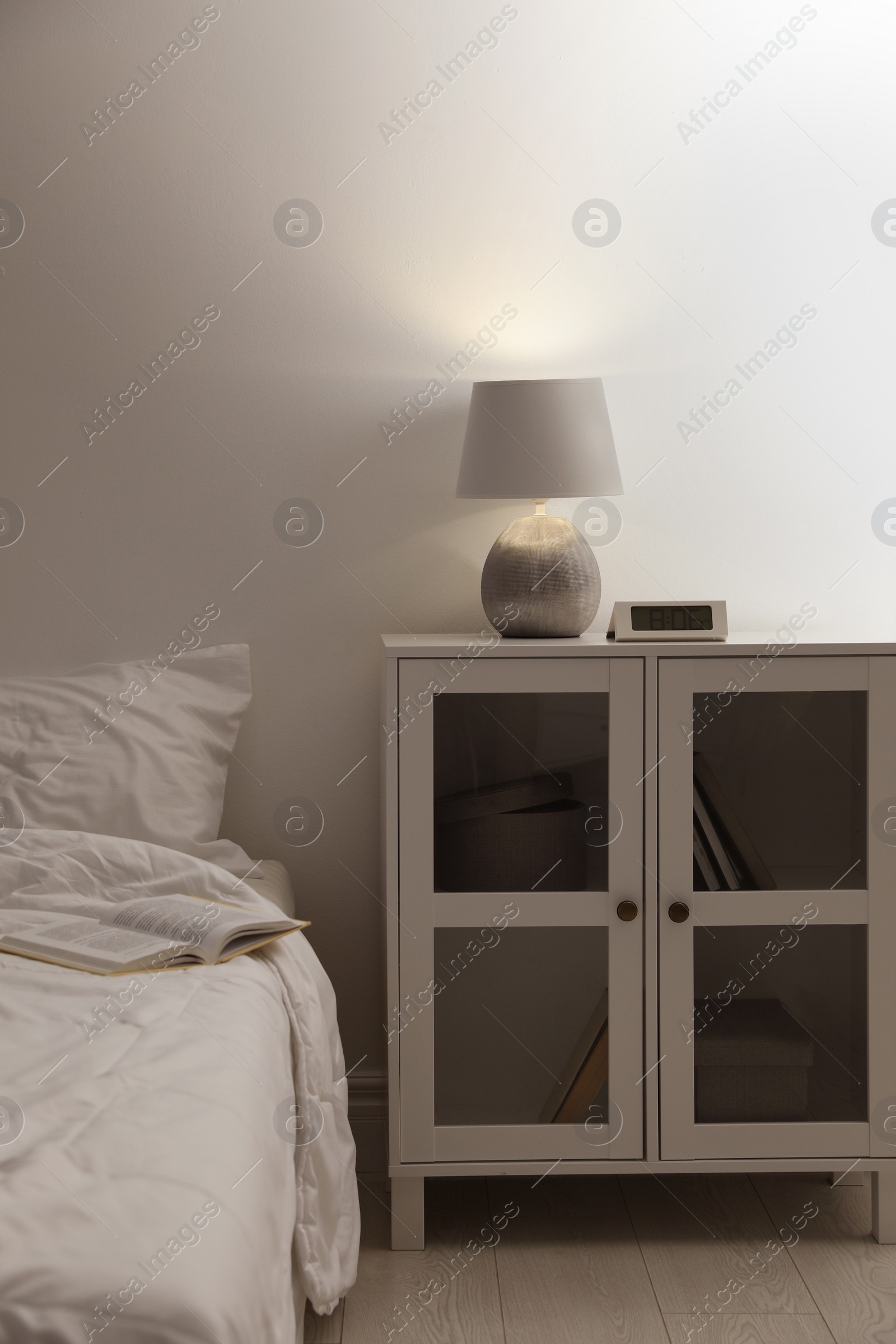 Photo of Stylish lamp and alarm clock on bedside table indoors. Bedroom interior elements