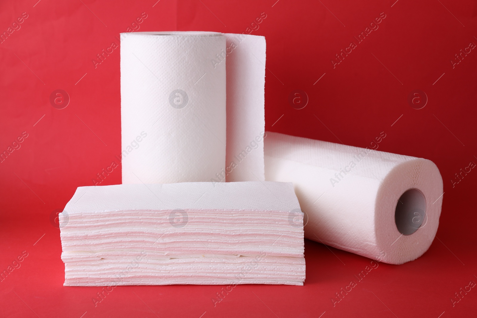 Photo of Rolls and stack of paper towels on red background