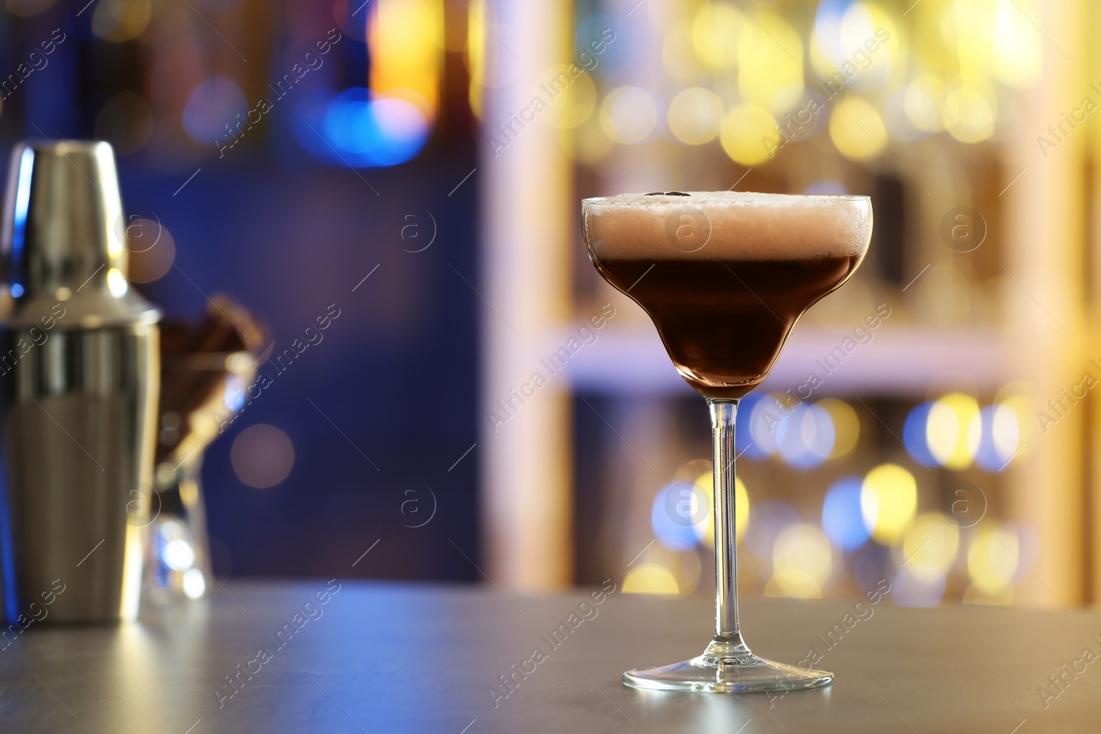 Photo of Glass of Espresso Martini on counter in bar, space for text. Alcohol cocktail