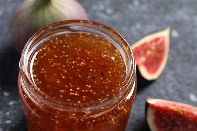 Photo of Glass jar with tasty sweet jam and fresh figs on table, closeup