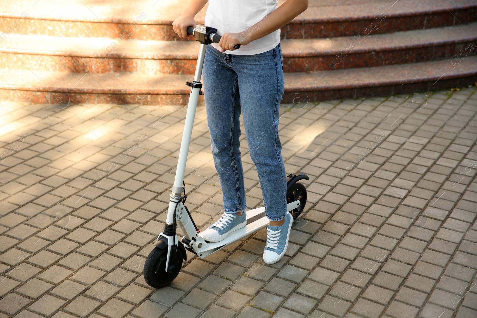 Photo of Woman riding electric kick scooter outdoors on sunny day