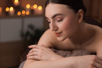 Photo of Spa therapy. Beautiful young woman lying on massage table in salon, space for text