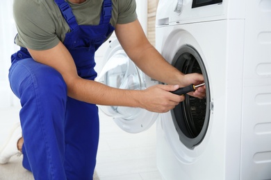 Young handyman fixing washing machine, closeup. Laundry day