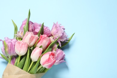 Photo of Beautiful bouquet of colorful tulip flowers on light blue background, top view