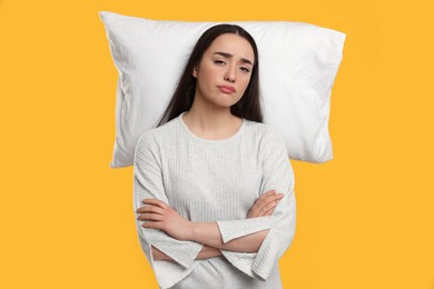 Photo of Tired woman with pillow on yellow background. Insomnia problem