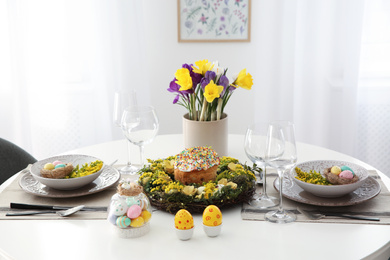 Festive Easter table setting with beautiful flowers and eggs indoors