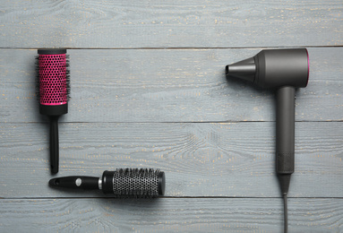 Photo of Hair dryer and brushes on wooden table, flat lay with space for text. Professional hairdresser tool