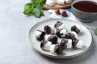 Delicious marshmallows covered with chocolate on light grey table