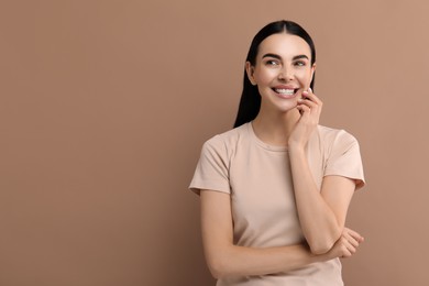 Beautiful woman with clean teeth smiling on beige background, space for text