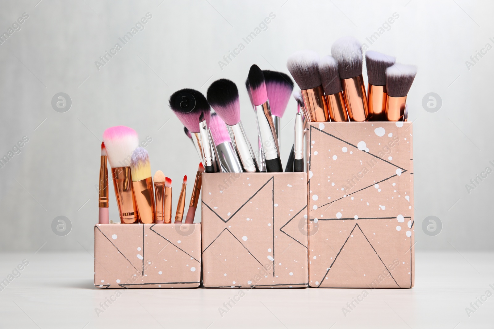 Photo of Organizers with professional makeup brushes on light table