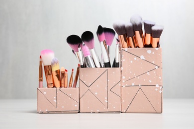 Photo of Organizers with professional makeup brushes on light table
