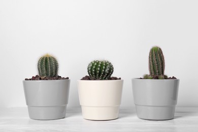 Different cacti in pots on white wooden table
