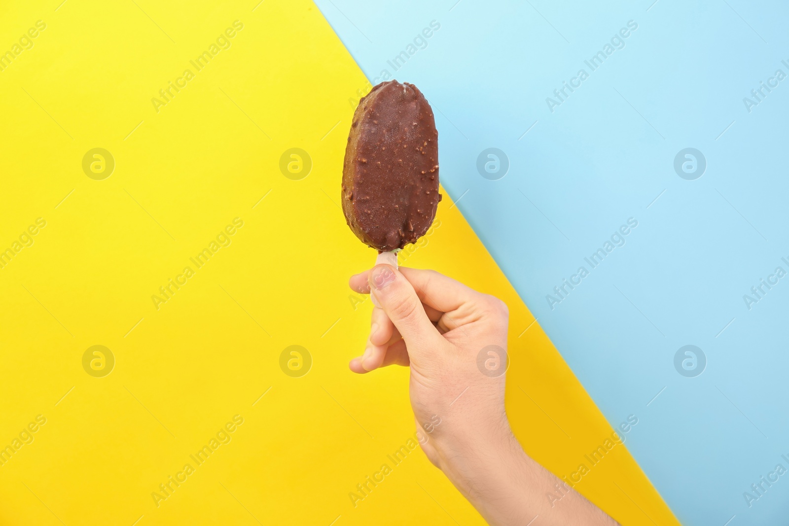 Photo of Man holding yummy ice cream on color background. Focus on hand