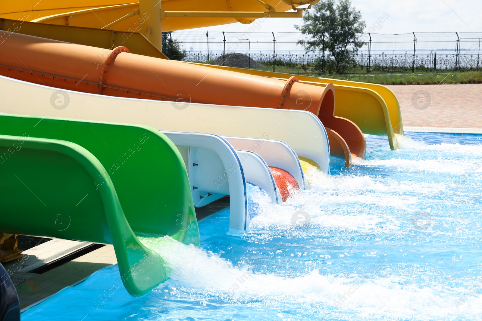 Photo of Different colorful slides and swimming pool in water park on sunny day