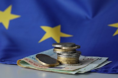 Photo of Coins, banknotes and European Union flag on table, closeup