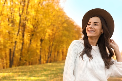 Beautiful happy woman wearing hat in park. Autumn walk