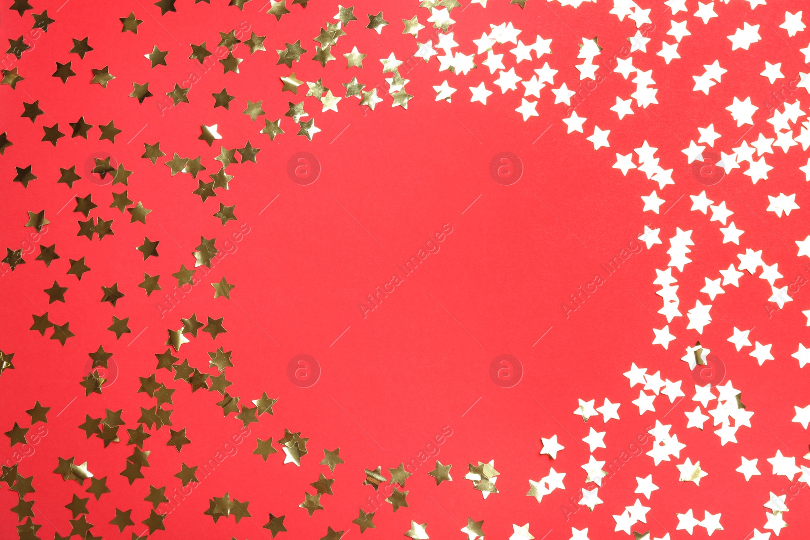 Photo of Frame of confetti stars with space for text on red background, top view. Christmas celebration