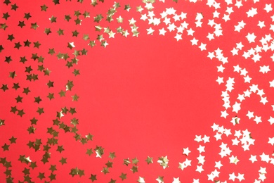 Photo of Frame of confetti stars with space for text on red background, top view. Christmas celebration