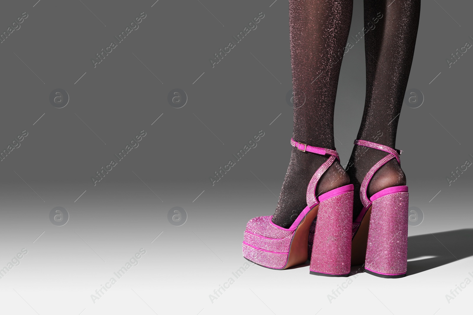 Photo of Woman wearing pink high heeled shoes with platform and square toes on light grey background, closeup. Space for text