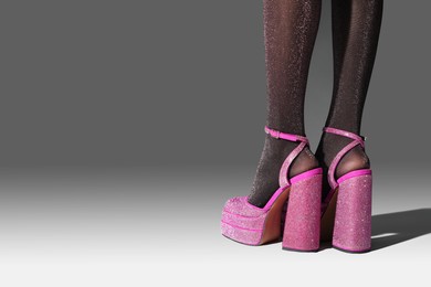 Woman wearing pink high heeled shoes with platform and square toes on light grey background, closeup. Space for text