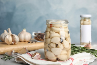 Composition with jar of pickled garlic on grey table against blue background