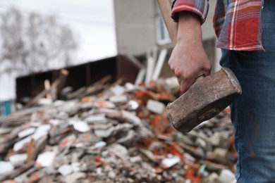 Photo of Man with sledgehammer near pile of broken stones outdoors, closeup. Space for text