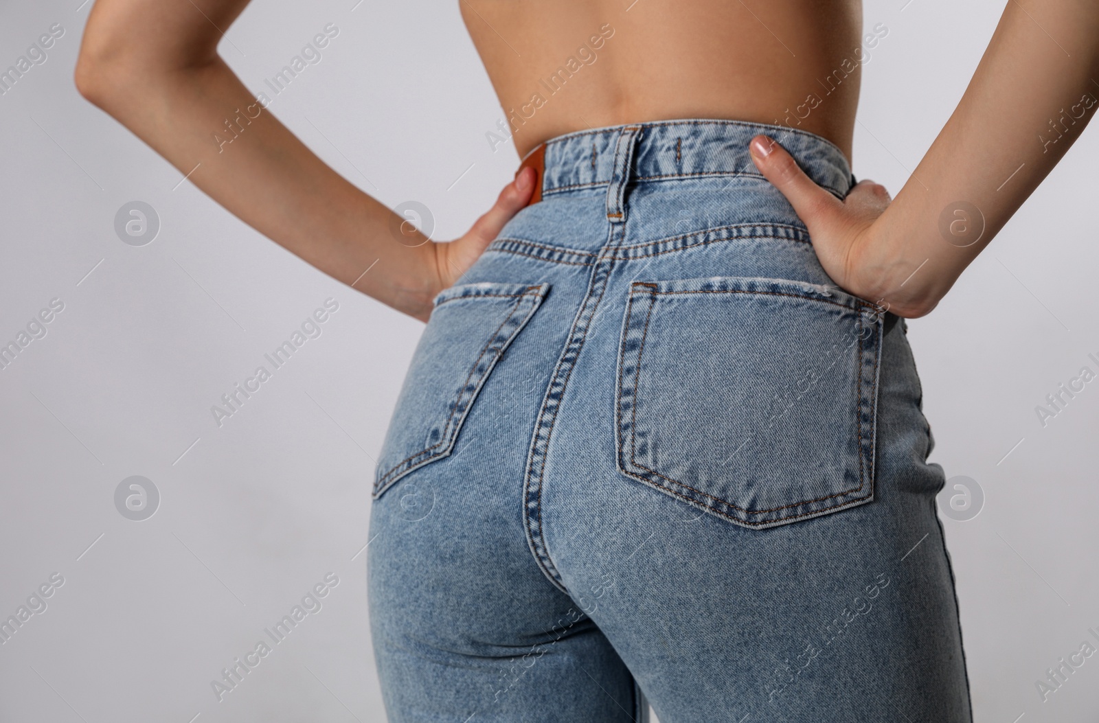 Photo of Woman in stylish jeans on light background, closeup