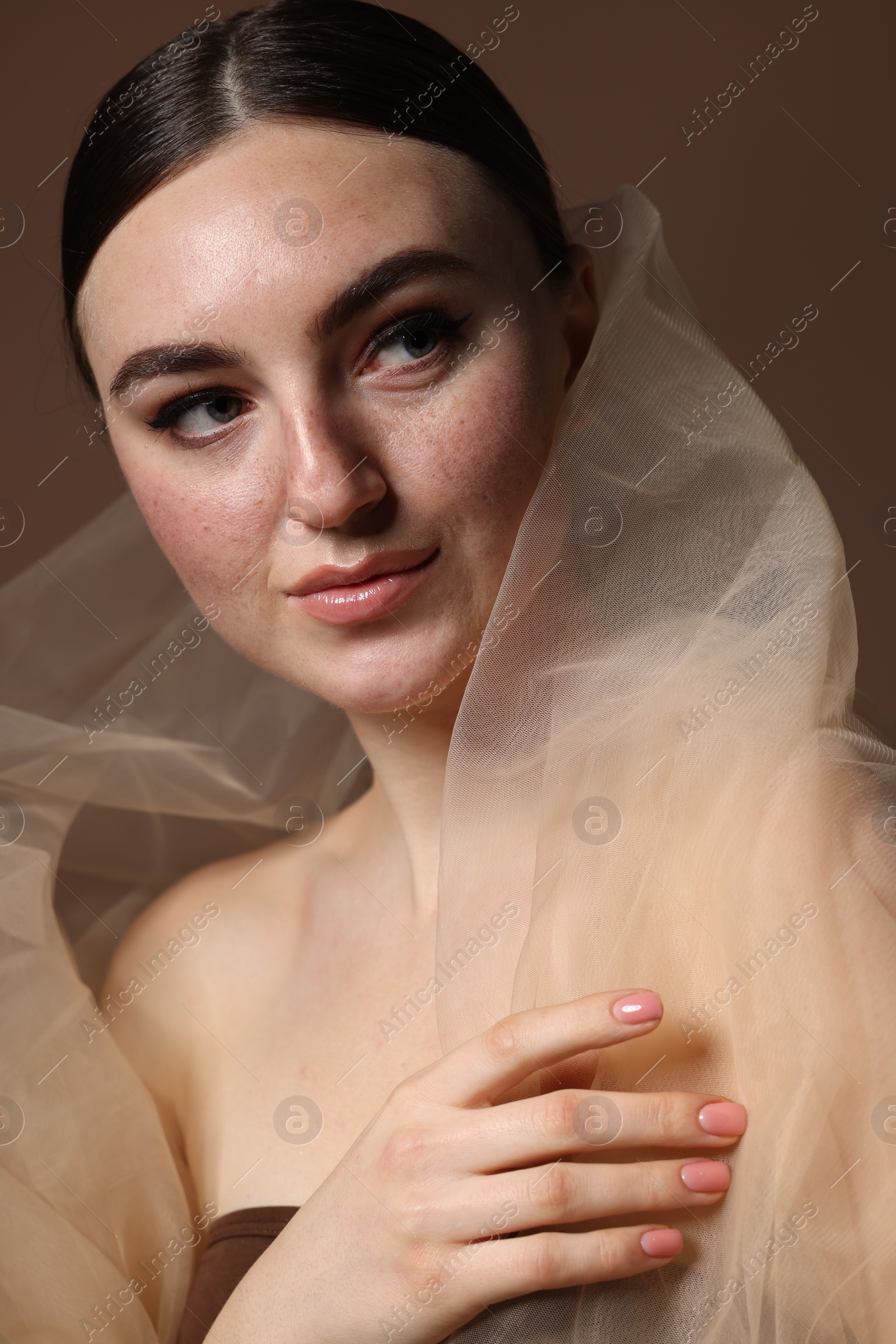 Photo of Fashionable portrait of beautiful woman with fake freckles on brown background