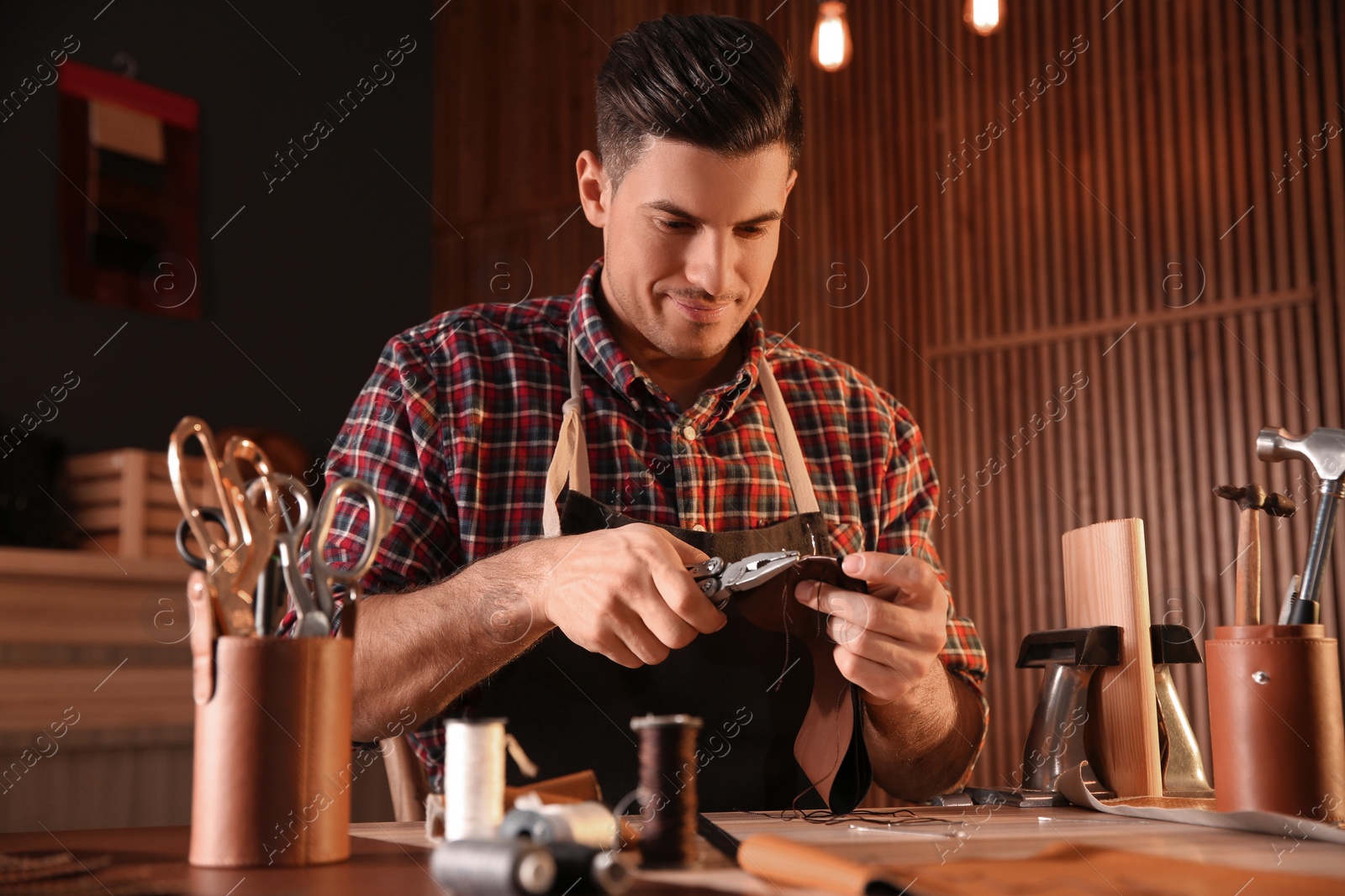 Photo of Man sewing piece of leather in workshop
