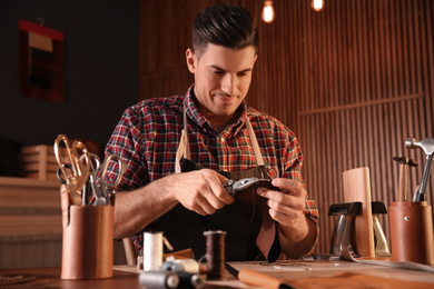 Man sewing piece of leather in workshop