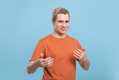 Photo of Happy man inviting to come in against light blue background