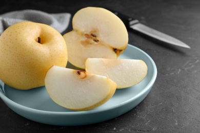 Photo of Cut and whole apple pears on black table, closeup