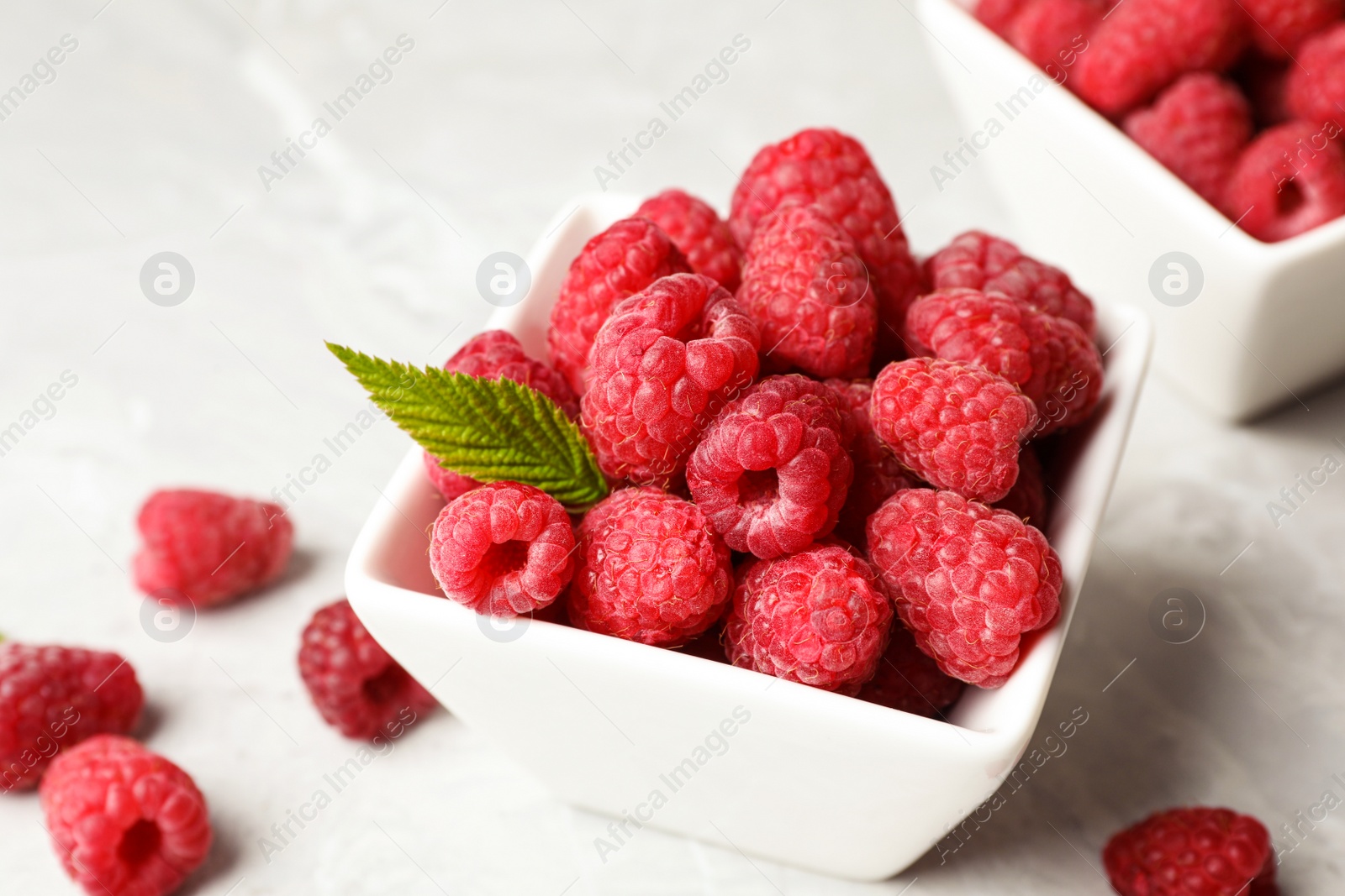 Photo of Bowl with delicious ripe raspberries on light background, closeup