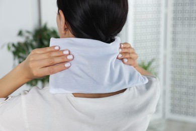 Photo of Woman using heating pad on neck at home, closeup