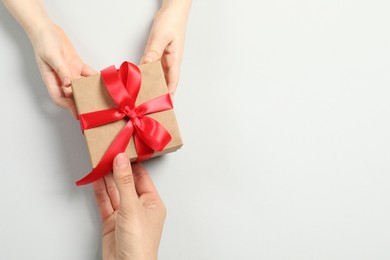 Photo of Mother giving gift box to her child on white background, top view. Space for text