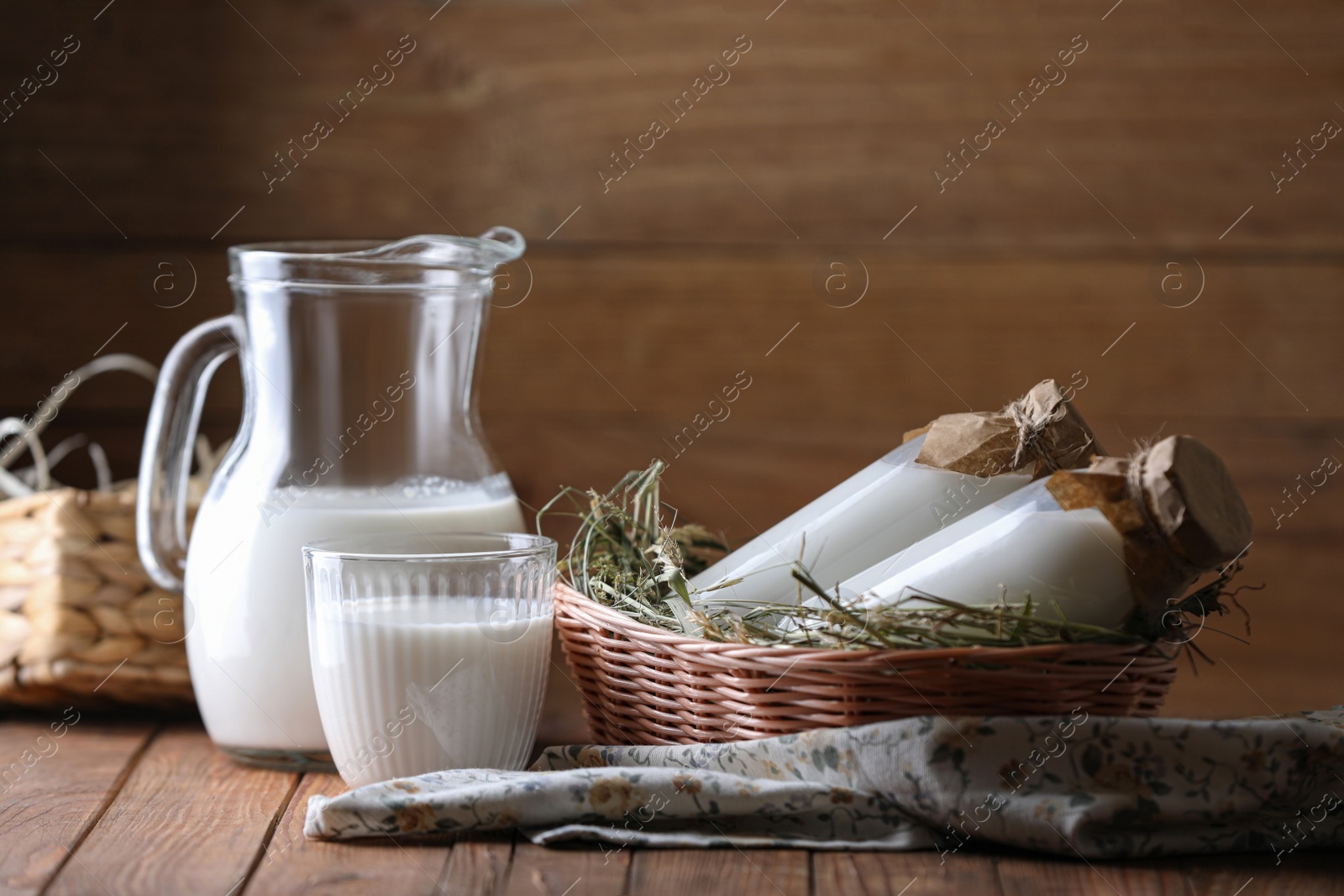 Photo of Tasty fresh milk in jug, bottles and glass on wooden table