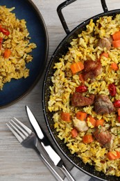 Photo of Delicious pilaf with meat, carrot and chili pepper served on wooden table, flat lay