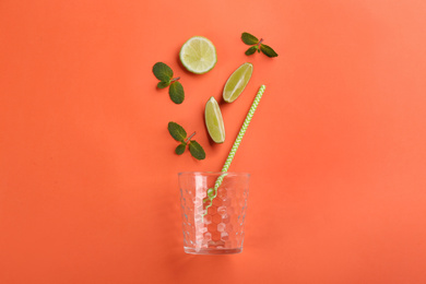 Photo of Creative lemonade layout with lime slices and mint on coral background, top view