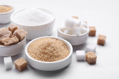 Different types of sugar on white table, closeup