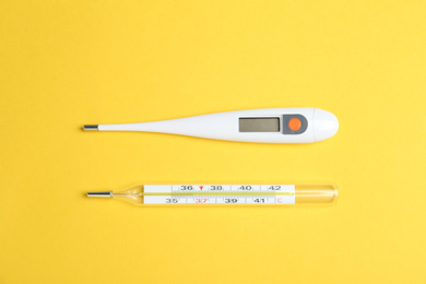 Different thermometers on yellow background, flat lay