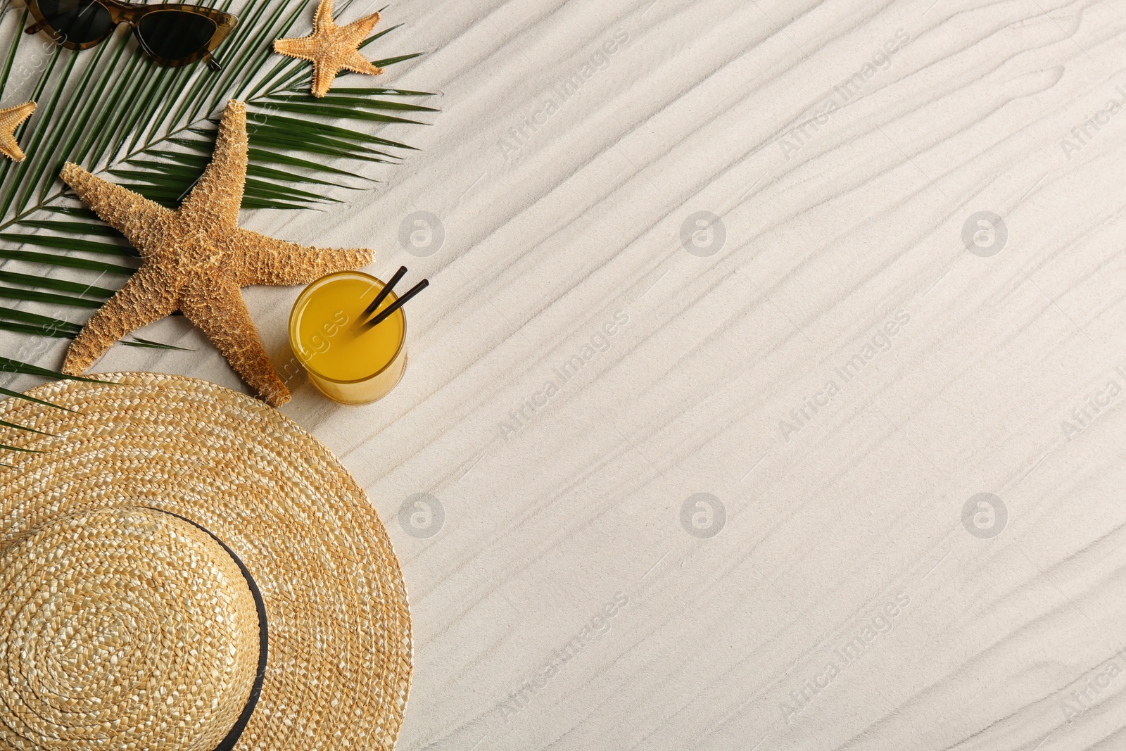 Photo of Different beach accessories and glass of cocktail on sand, flat lay. Space for text